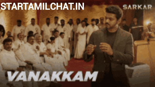 a man in a suit stands in front of a group of people with the words vanakkam on the bottom