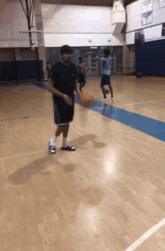 a man dribbles a basketball on a basketball court while another man watches