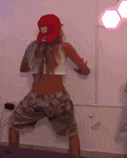 a woman wearing a ny hat is dancing in front of a white wall