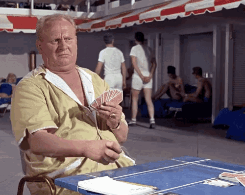 a man sitting at a table holding a deck of playing cards