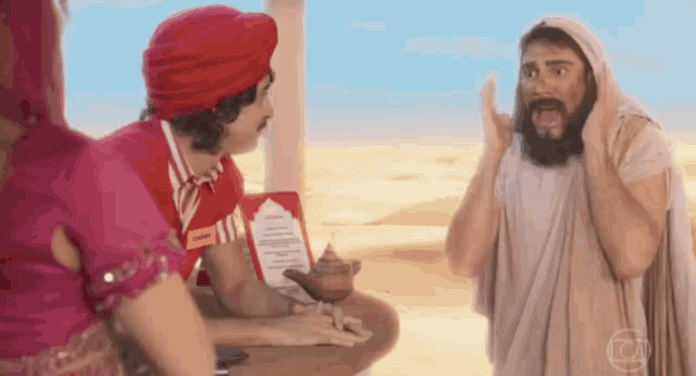 a man with a beard and a turban is talking to a woman in a pink dress and a man in a white robe