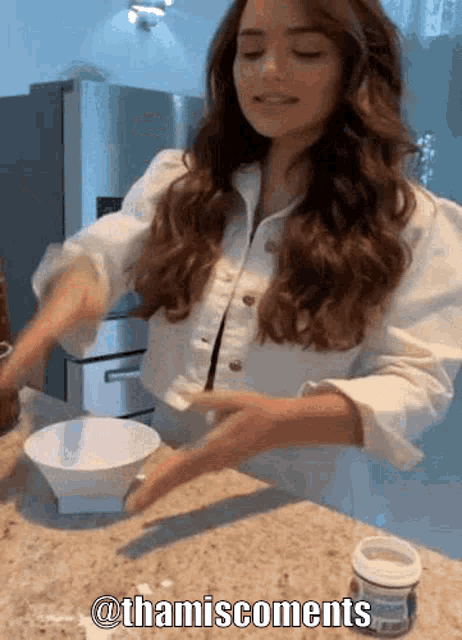 a woman in a white shirt is mixing something in a bowl with a caption that says @thamiscomments