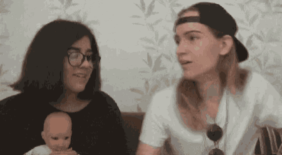 two women are talking to each other while holding a doll .