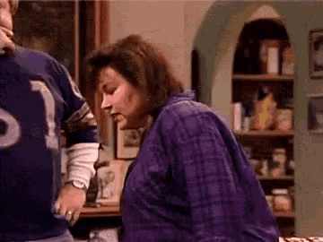 a woman in a purple plaid shirt is standing next to a man in a blue jersey .