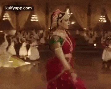 a woman in a red dress is dancing in a room with a group of people .