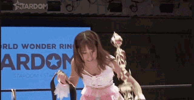 a woman in a pink dress is holding a trophy in her hand .
