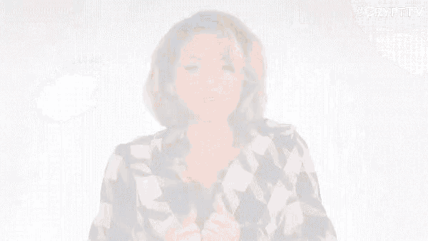a woman in a plaid jacket is taking off her jacket and looking at the camera .