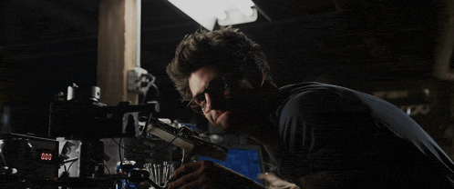 a man wearing glasses is holding a spider web in his hands