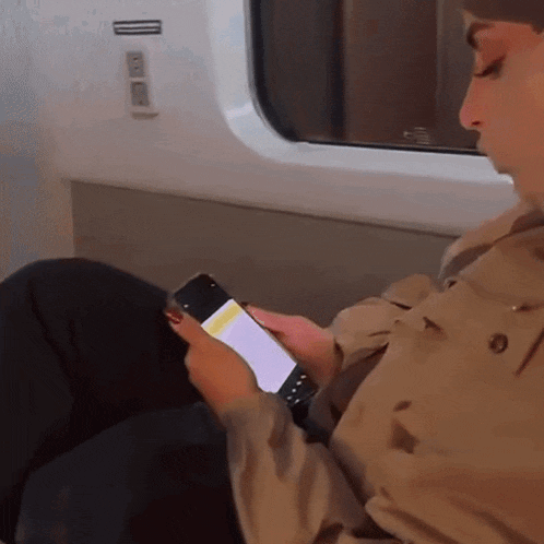 a man sitting on a train looking at his phone