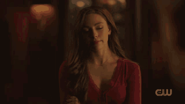 a woman in a red top with the cw logo on the bottom right