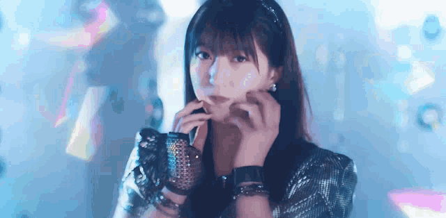 a close up of a woman 's face with her hands on her face and a blue background .
