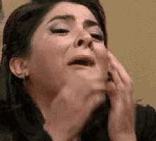 a close up of a woman 's face with her mouth open and her hands on her face .