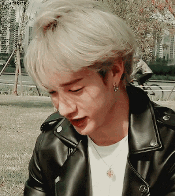 a close up of a person wearing a leather jacket and a necklace
