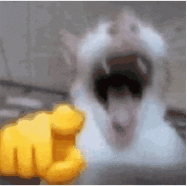 a close up of a cat with its mouth open and a yellow fist pointing at it