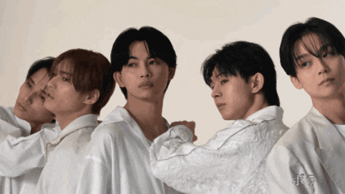 a group of young men are standing in a row and one of them is wearing a white shirt with chinese writing on it