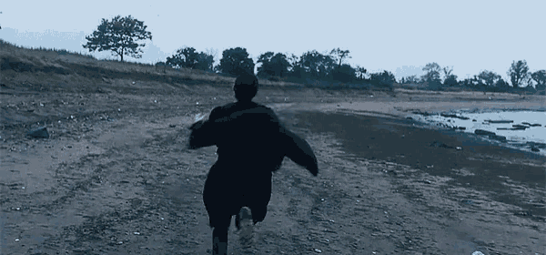 a person in a black jacket is running on a beach