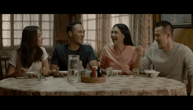 a group of people are sitting around a table with bowls of food