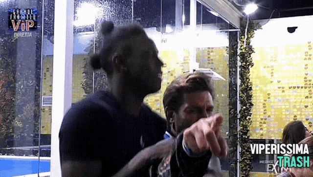two men are pointing at each other in front of a sign that says vip
