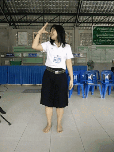a woman in a white shirt with a name tag that says ' a ' on it stands in front of blue chairs