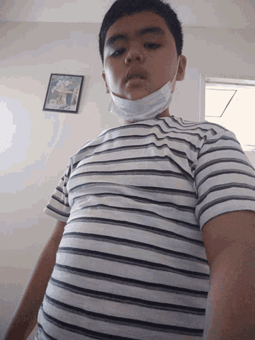 a young boy wearing a striped shirt and a mask