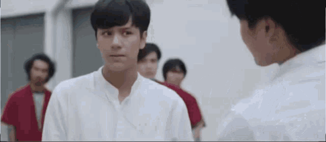 a group of young men are standing next to each other in a room and talking to each other .