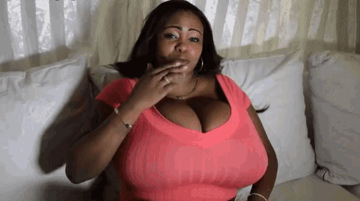 a woman with very large breasts sits on a couch