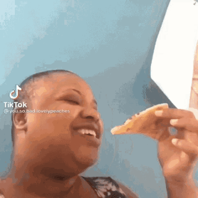 a woman is eating a slice of pizza with a funny face .
