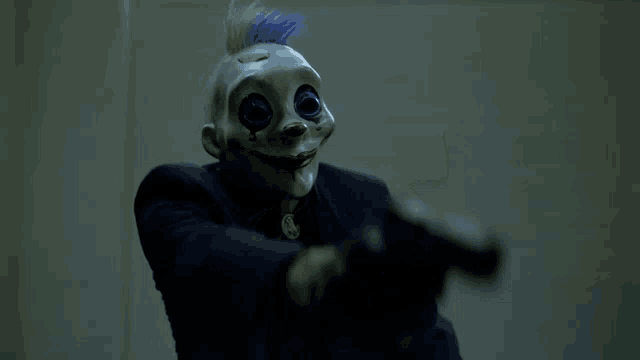 a man wearing a clown mask points a gun