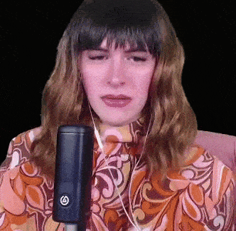 a woman singing into a microphone with the letter g on the side