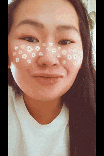 a woman with flowers on her face looks at the camera