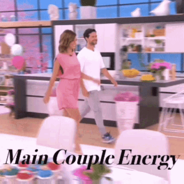 a woman in a pink dress and a man in a white shirt are walking in a kitchen with the words main couple energy written below them