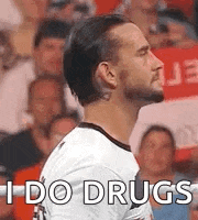 a man in a white shirt is standing in front of a crowd of people and says `` i do drugs '' .