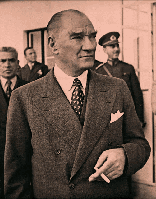 a man in a suit and tie holds a cigarette in his right hand