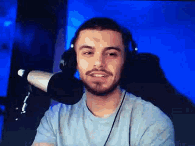 a man with a beard and headphones is sitting in front of a microphone and smiling .
