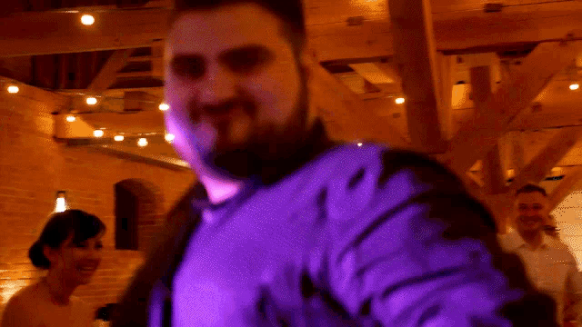 a man in a purple shirt is dancing in a room