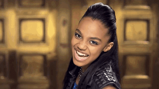 a woman with a ponytail is smiling in front of a gold door
