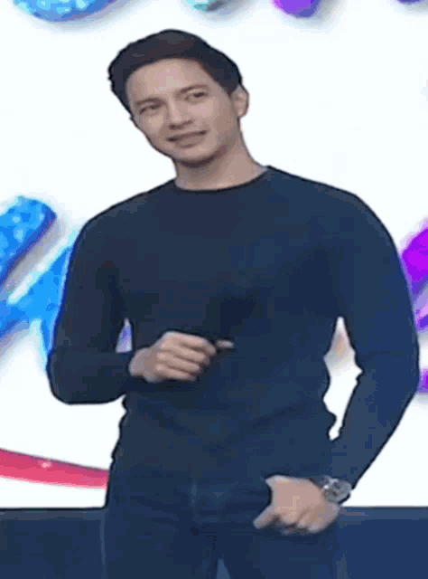 a man wearing a black shirt and a watch is standing in front of a colorful background .