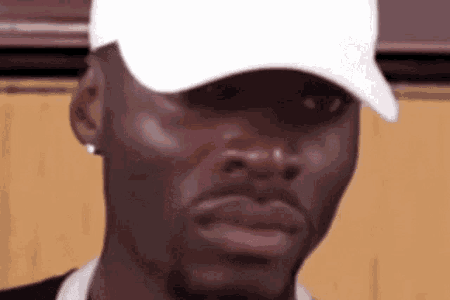 a close up of a man wearing a white hat and earring .