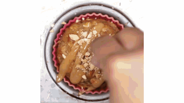 a person is putting nuts on a muffin in a cup .