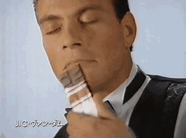 a man in a tuxedo eating a piece of chocolate with jc written on the bottom right