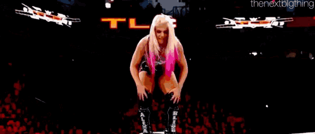 a woman is standing on a rope in a wrestling ring holding a trophy .