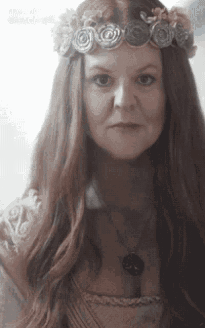 a woman with long red hair wearing a necklace and a flower crown
