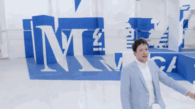 a man in a suit stands in front of a blue and white sign that says ' mccall '