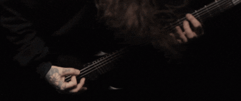 a close up of a person playing a guitar in the dark