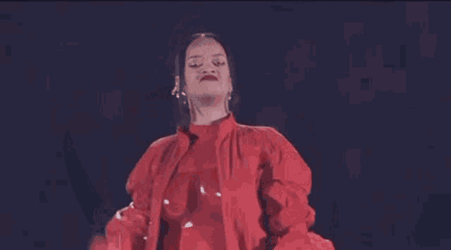 a woman in a red jacket and gloves is dancing on stage .