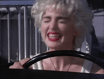 a woman is driving a car with her eyes closed and a smile on her face .