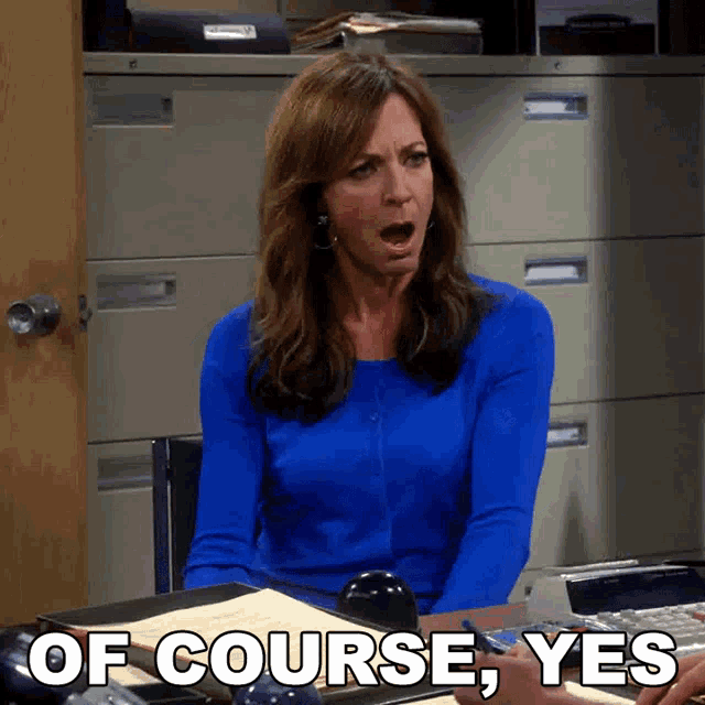 a woman in a blue shirt is sitting at a desk with the words of course yes above her