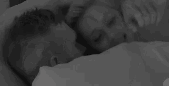 a black and white photo of a man and woman laying in bed .