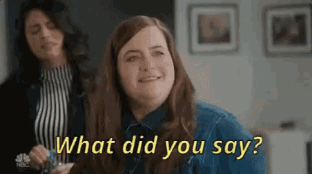 a woman is smiling and holding a glass of wine while another woman says what did you say .