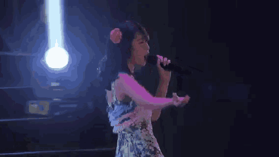 a woman in a floral dress is singing into a microphone .